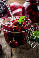 Homemade preserved cherry and mint jam, with fresh cherries on rustic old wooden background copy space