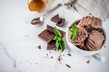 Homemade chocolate ice cream served with fresh mint, dark chocolate and waffle ice cream cones, white marble background copy space top view