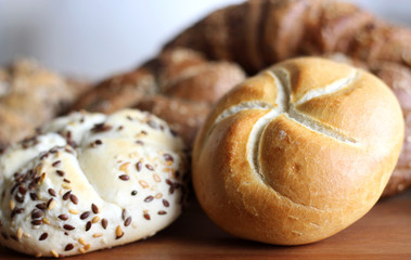 Fresh crusty bread roll with linseed and sunflower seed on wood background.