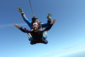 Skydiving. Two men are flying in the blue sky.