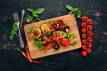 Grilled vegetables on a wooden board. On a wooden background. Top view. Copy space.