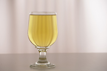 ein gelbes getränk im glas auf hellem untergrund