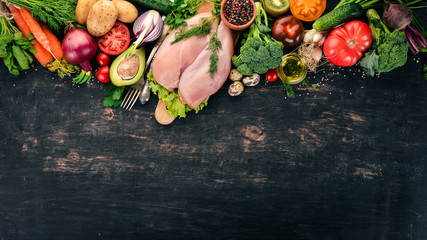 Chicken breast and fresh vegetables. Healthy food. On a black wooden background. Top view. Copy...