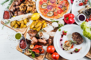 Big set of different dishes with meat, vegetables, pizza and spices flatlay on white background