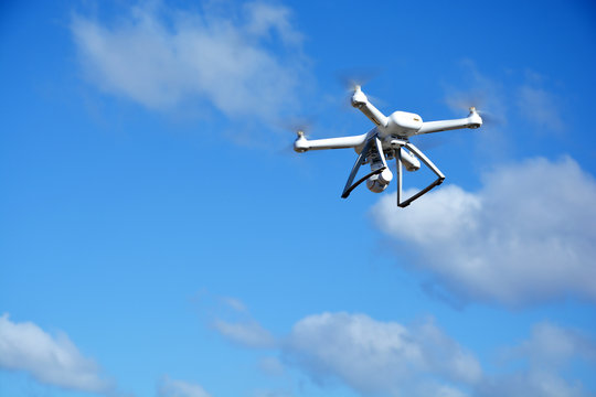 White modern drone with camera flying on sky background