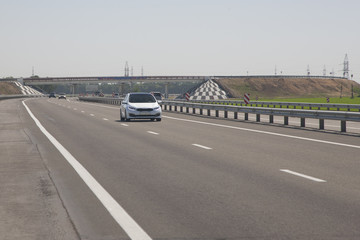 Several cars are driving along the highway. In the background, the bridge