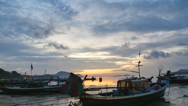 time lapse sunrise above fishing boats in Rawai sea during high tide