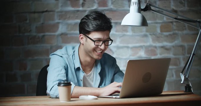 young handsome asian student laughing in loft room 4k dollyshot