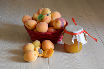 Red basket of fruit/Basket of apricots with a jar of jam made from the same fruit and externally a pair of fruits cut in two parts