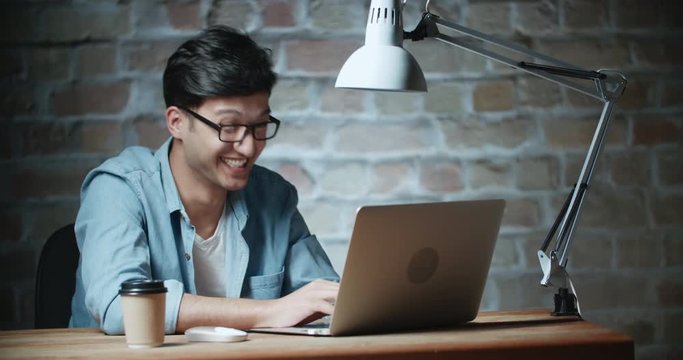 young handsome asian student laughing in loft room 4k dollyshot