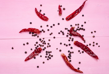 The black pepper seed and dried chili put on pink pastel timber board