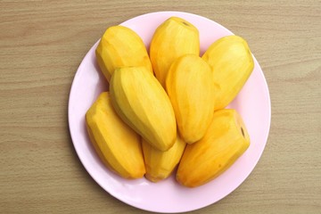 Ripe mango  in a pink plate on a wooden background.