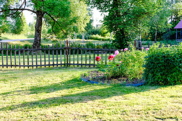 early morning in the countryside garden with wooden fence and sun rays