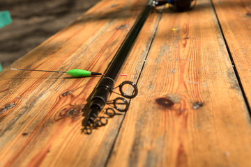 Fishing rod and spinning reel with line on wooden background with free space, Top view.