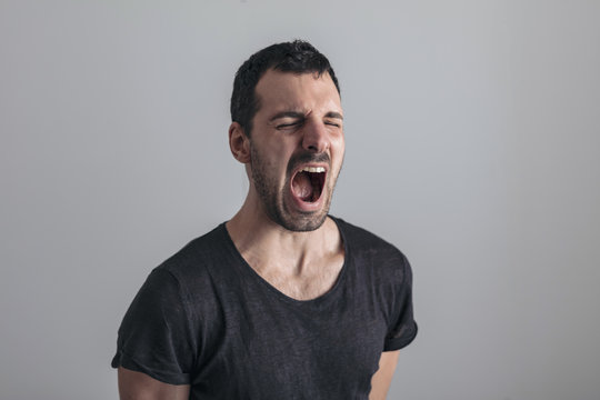 scared expression of a man who screams, isolated on gray background