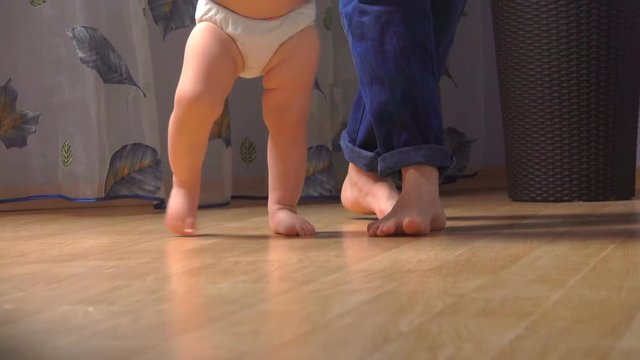 close-up of children's legs taking their first steps next to their mother