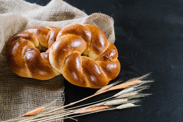 Fragrant fresh buns with wheat flakes on black wooden background