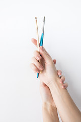 Two paint brushes in women hands on white background isolated