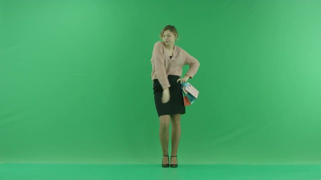 Pretty shopping woman is dancing with shopping bags. Female shopper holding shopping bags front on green background in studio.