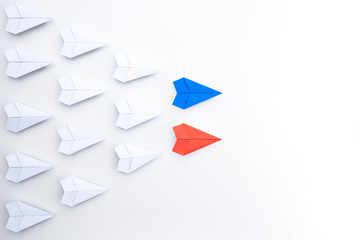 Blue and red paper plane leading among white. leaders of two business teams or competition of two leaders concept.