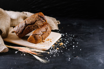 Sweet rye bread with different ingredients on black wooden background