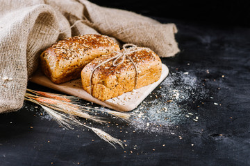 Sweet rye bread with different ingredients on black wooden background