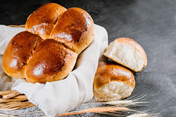 Sweet fresh buns in the basket on black wooden background