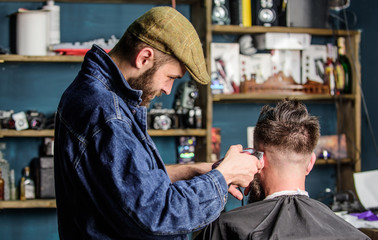 Barber with clipper trimming hair of client, rear view. Barber with hair clipper works on short...