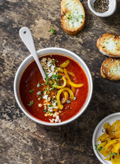 Vegetarian tomato soup with baked yellow sweet pepper on wooden background, top view