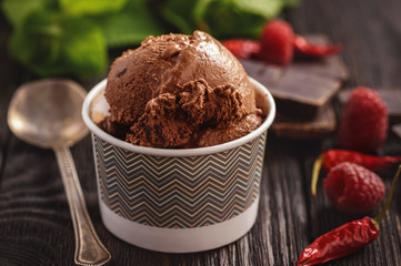 Chocolate ice-cream with raspberries on dark wooden background.