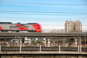 Fast modern metro train on the city background. Sunny day with the clear sky. Blurred motion.