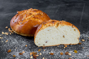Sweet tasty buns with raisins on black wooden background
