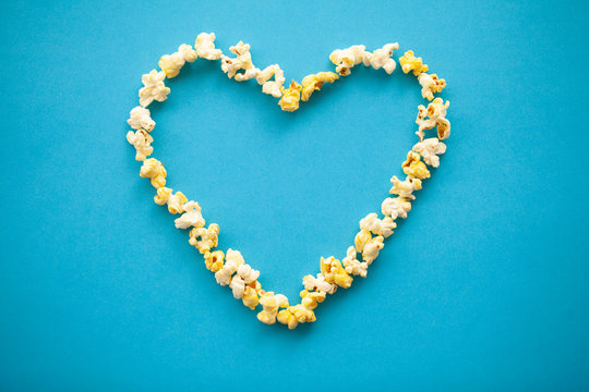 Food. Image of the Heart Forms from Popcorn. Delicious Popcorn on Blue Background. Cinema.