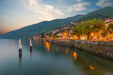 holidays in Italy - a view of a city Bellano, with the most  beautiful lake in Italy - Lago di Como in background. Area of famous Belano City at sunset. Harbor with boats and yachts