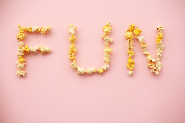 Food. Word of Fun. Popcorn bucket. Delicious Popcorn on Pink Background. Cinema.