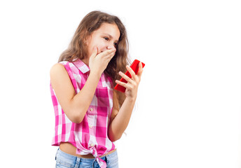 Cute little girl looks in smartphone and covers her mouth in surprise