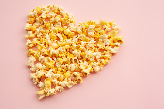 Food. Image of the Heart Forms from Popcorn. Delicious Popcorn on Pink Background. Cinema.