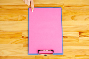 Office Hand Holding a Folder with a Pink Color Paper on the Background of the Wooden Table. Copyspace. Place for Text.