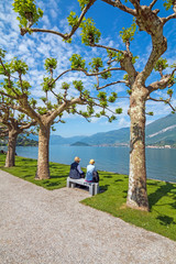 Shot of a senior couple sitting on a bench in the park in Villa Melzi near Bellagio at the famous Italian lake Como in May