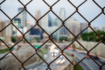 Naklejka premium Long exposure shot of 24th Street pedestrian bridge, through the fencing over 35W highway. Car headlight trails Minneapolis Minnesota USA