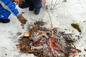 People roast sausages at the stake in nature in the forest. Picnic in nature. Russia, January, 2018.