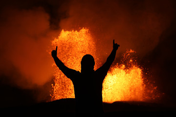 Fototapeta premium Victory pose in front of a lava fountain of the volcanic eruption of Kilauea in Hawaii