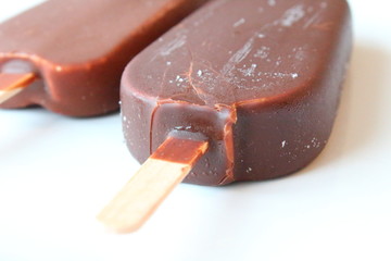 Creamy ice cream on a stick in chocolate glaze on a white plate. Eskimo. Close-up. Background.