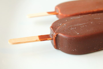 Creamy ice cream on a stick in chocolate glaze on a white plate. Eskimo. Close-up. Background.