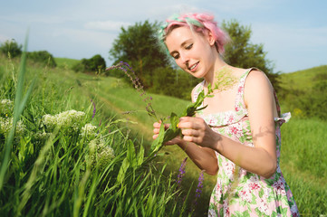 Portrait of a happy young cute girl with multi-colored hair collects flowers next to a country road at sunset. The concept of human harmony with the nature of spring and happiness
