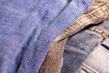 A pile of blue and black jeans. Denim. Close-up. Background. Texture.