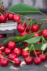 Cherries with leaves in vintage wooden box on rustic wooden table. Copy space