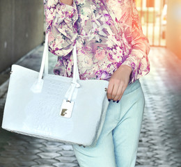 Elegant woman wearing  silk floral print blouse with trendy violet color and pants holding leather...