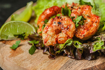 Roasted fried shrimps with green salad and lime on wood, 