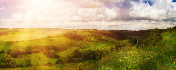 Rural landscape with fields, waves and blue sky with clouds, spring seasonal natural background